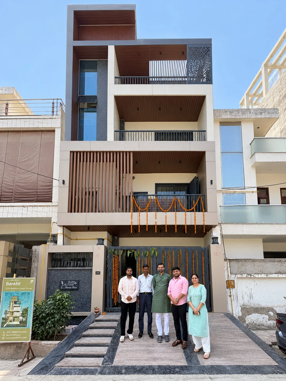 The same Linear House elevation built on site, with the UrbanKriti team at the gate
